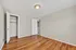 Spacious room with elegant hardwood floors, fresh neutral walls, and a bright ceiling light. Features an open closet and a sleek white door.