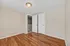 Bright, empty room with polished hardwood floors and neutral walls, featuring double doors for ample storage.