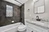 Modern bathroom featuring sleek black fixtures, granite countertop, and elegant tiled walls with a decorative glass window.