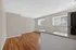 Bright and inviting living area with hardwood floors and large windows, featuring a stylish granite countertop in the kitchen.