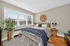 Bright and cozy bedroom with a large window, inviting natural light, stylish decor, and wooden flooring.
