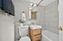 Elegant bathroom featuring a sleek vanity with wood finish, stylish gold fixtures, and contemporary tiled walls.