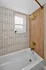 Elegant bathroom featuring a luxurious bathtub, modern gold fixtures, and stylish tile accents with natural light from the window.