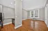 Bright, open-concept living area with sleek hardwood floors, modern kitchen, and large windows offering natural light.