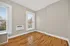 Bright, airy room with polished hardwood floors, large windows, and a wall-mounted air conditioner, offering a modern and inviting space.