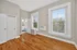 Bright bedroom with hardwood floors, large windows featuring blinds, and a spacious closet area.