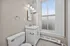 Elegant bathroom featuring a white vanity with marble countertop, large window for natural light, and modern lighting fixtures.