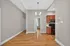 Elegant apartment interior featuring hardwood floors, modern lighting, and a kitchen with wooden cabinets and stainless steel appliances.