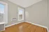 Bright and airy room with hardwood floors, large windows, and an in-wall air conditioning unit.