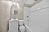 Modern bathroom with sleek white vanity, stylish lighting, and pristine bathtub enhancing the contemporary apartment feel.