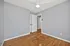 Bright bedroom with sleek wood flooring, modern ceiling fan, and light gray walls, offering a spacious and cozy ambiance.