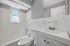 Modern bathroom with sleek fixtures, bright white tiles, and a large window bringing in natural light.