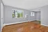 Bright and airy living space featuring large windows, fresh grey walls, and polished wooden floors, perfect for a cozy and inviting atmosphere.