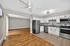 Inviting open-concept kitchen and living area with sleek stainless steel appliances, elegant white cabinetry, and warm hardwood flooring.