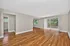 Spacious living room with polished hardwood floors, large windows for natural light, and access to a private balcony.
