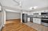 Modern open-concept kitchen and living area with hardwood flooring, featuring sleek stainless steel appliances and white cabinetry.