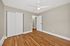 Bright and airy empty bedroom featuring sleek hardwood flooring, a modern ceiling fan, and built-in closet.