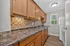 Modern kitchen with warm wooden cabinetry, sleek countertops, and a bright window view.
