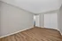 Elegant room with warm wood flooring, neutral walls, and modern closet sliding doors, offering a spacious and versatile living area.