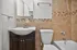 Elegant bathroom featuring a modern sink with chrome fixtures, white toilet, and a cozy bathtub surrounded by neutral tile accents.