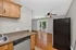 Bright kitchen and living area with sleek countertops, modern appliances, and a ceiling fan, opening to a sunlit balcony.