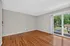 Bright and airy room with polished hardwood floors and sliding glass doors opening to a lush green view.