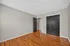Bright and spacious bedroom with sleek hardwood floors and modern dark wood accents.