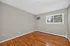 Bright and spacious room with polished hardwood floors, large window with lush green view, and modern neutral walls.