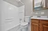 Modern bathroom featuring a clean design with a white bathtub, classic wooden vanity, and elegant wall mirror.