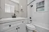 Elegant modern bathroom with sleek white fixtures, black accents, and natural light from a textured window.