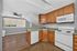 Charming kitchen with warm wooden cabinetry, modern appliances, and spacious countertops, featuring a cozy adjacent living space with natural light.