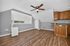 Bright, modern living space featuring rich hardwood floors, sleek ceiling fan, and compact kitchen area with elegant wooden cabinets.