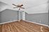 Spacious attic room with sleek wooden floors, modern gray walls, and a ceiling fan, ideal for a cozy living area.