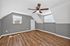 Charming attic room with polished wooden floors and a ceiling fan, ideal for a cozy retreat.