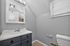 Modern bathroom with sleek gray walls, a white vanity, and a toilet, exuding contemporary elegance.