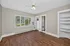 Bright room with elegant hardwood flooring, large windows offering scenic views, built-in shelving, and a ceiling fan. Ideal for a cozy living space.