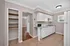 Modern kitchen with sleek white cabinets, integrated appliances, and stylish open shelving, featuring natural light and tiled flooring.