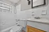 Charming bathroom with classic white tiles, a sleek showerhead, and a stylish vanity.