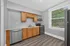 Modern kitchen with sleek stainless steel appliances, wood cabinetry, and large window for natural light.