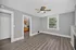 Bright, spacious living area with modern flooring, ceiling fan, and large window, connecting to a cozy kitchen with wooden cabinetry.