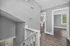 Modern hallway with fresh gray walls and sleek wooden flooring, leading to bright, spacious rooms with large windows.
