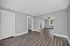 Spacious open living area with elegant wood flooring, large windows, and modern neutral walls.