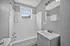 Bright, modern bathroom featuring a clean white bathtub, sleek vanity, and large mirror with natural light pouring in from a window.