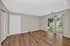 Spacious living room with elegant laminate flooring and large sliding glass doors opening to a lush garden view.