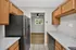 Contemporary kitchen featuring sleek black appliances, elegant marble countertops, and ample wooden cabinetry opening to a bright living area.