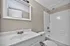 Bright, modern bathroom featuring a sleek vanity, elegant mirror, and a pristine bathtub with shower fixture.