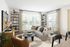 Bright and inviting living room with modern decor, plush gray sofa, and large windows offering abundant natural light.