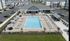 Luxurious apartment complex featuring a sparkling outdoor pool surrounded by chic lounge chairs and stylish umbrellas, with elegant buildings in the background.