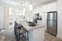 Modern kitchen with sleek granite countertops, stainless steel appliances, and stylish bar seating in a bright, open space.