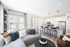 Modern open-plan living area featuring a cozy seating arrangement with plush cushions, a sleek kitchen with a breakfast bar, and large windows allowing natural light to flood the space.